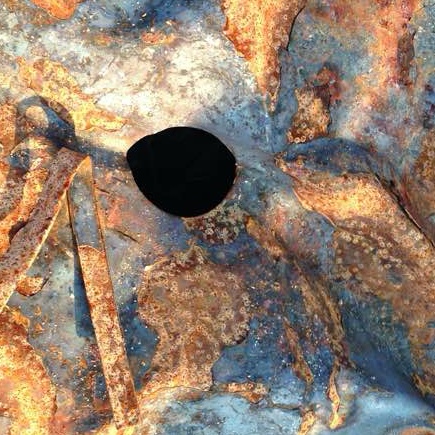 rusty iron with black holes and wire over