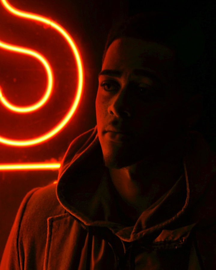 man in dark lit by red neon light