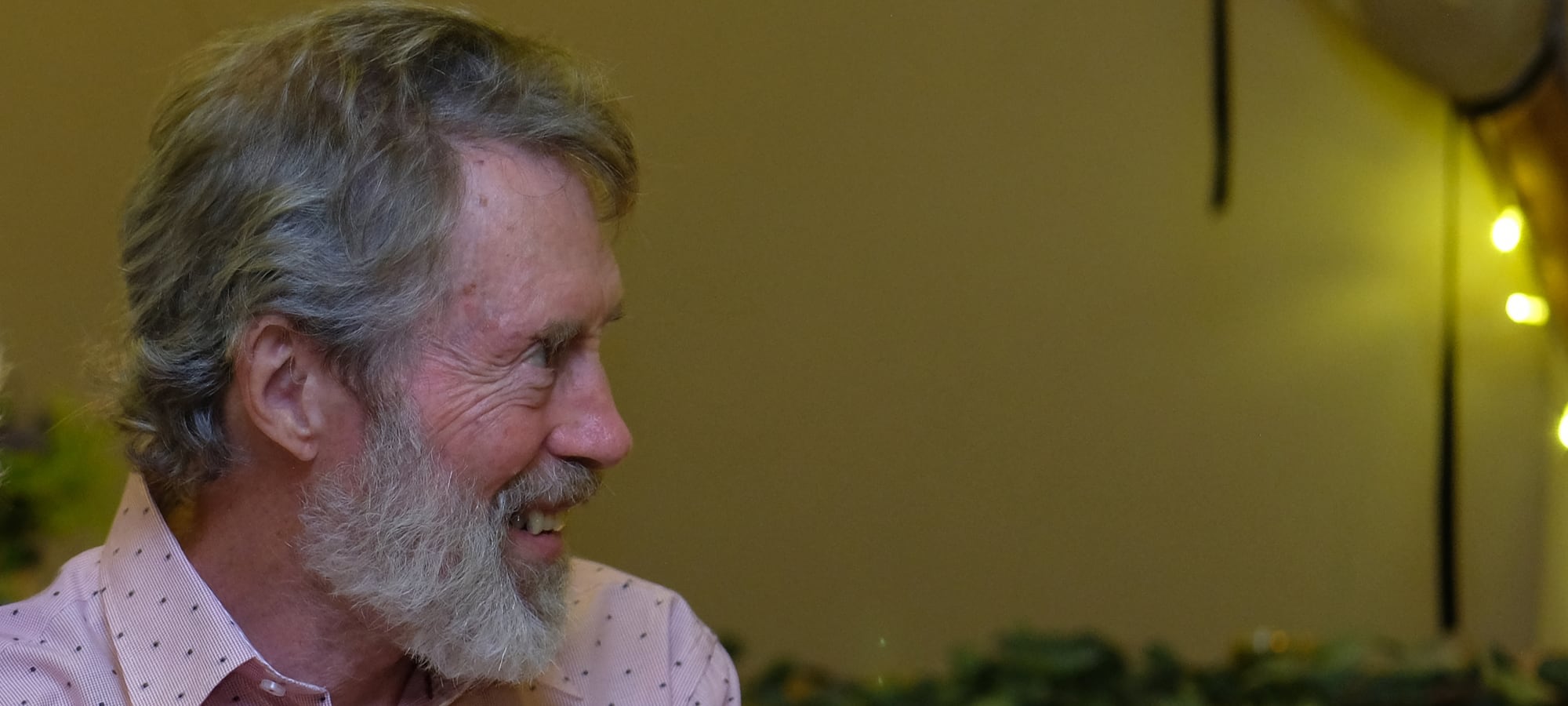 older man in profile, looks ahead in party tent at night
