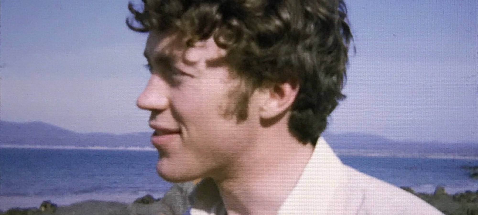 young man with sea and mountains in background