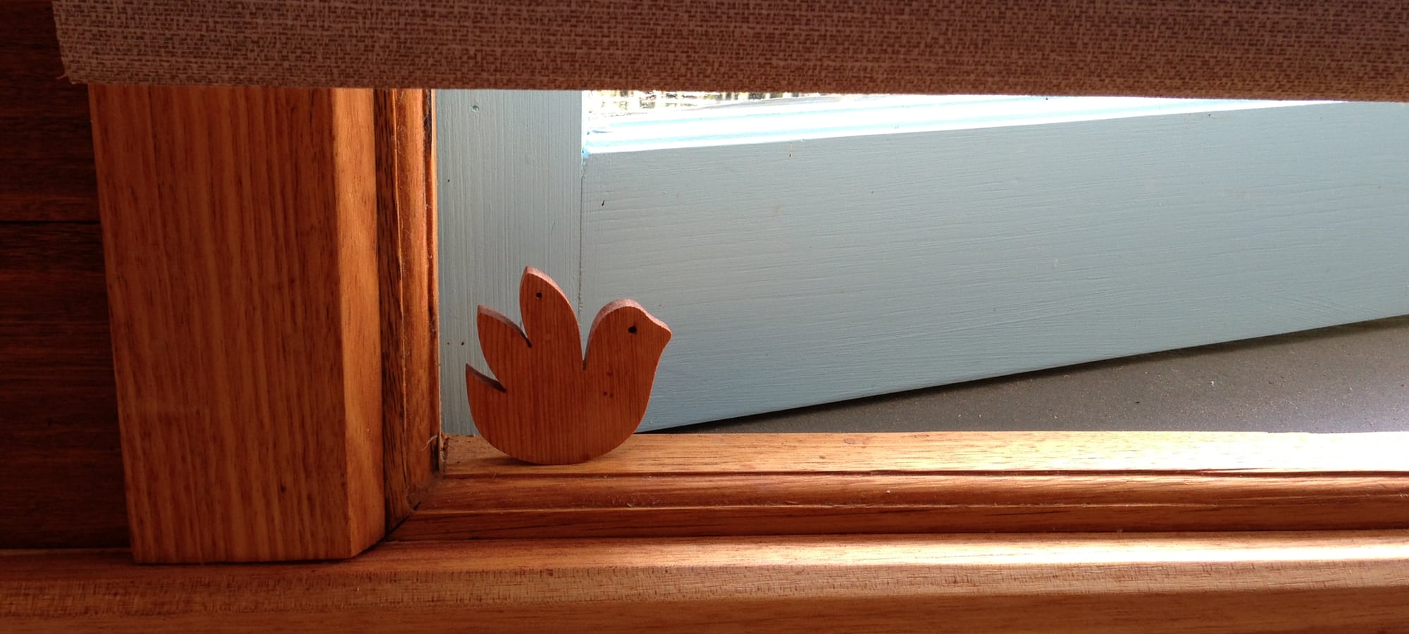 wooden bird in open window