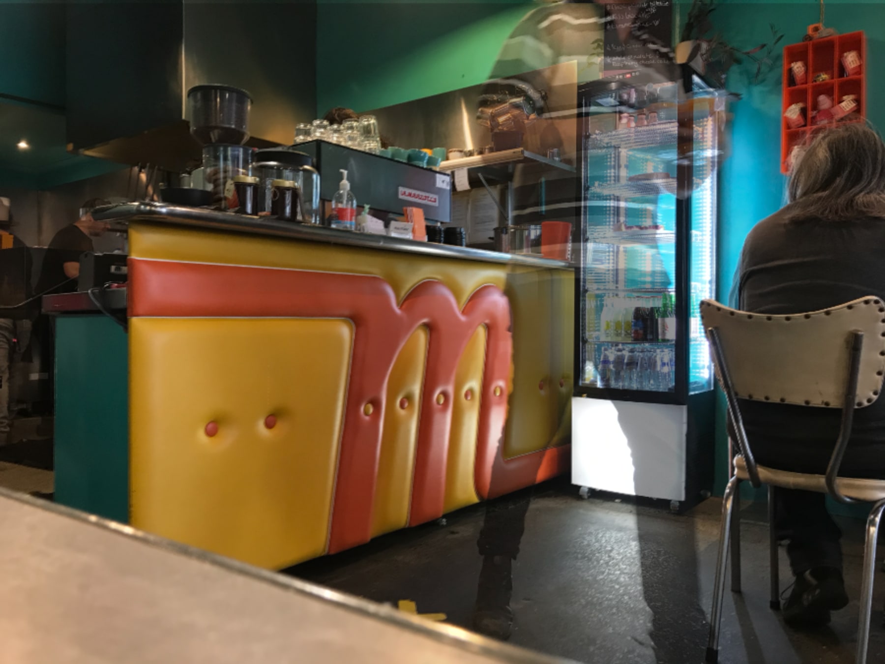 ghost waiter carries drinks from vinyl padded bar in cafe